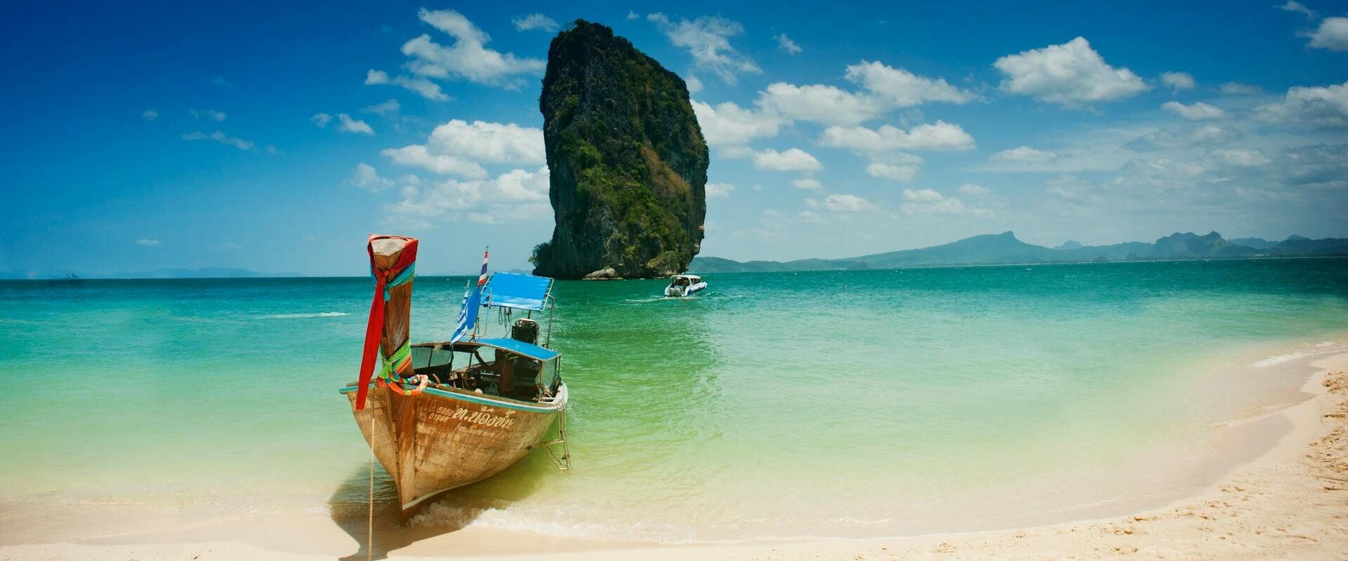 Krabi’s lush coastal landscape in Thailand on a Krabi Travel banner by Legend Travel Group.